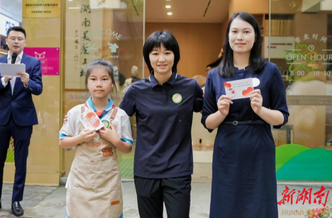 图为文晓燕为志愿者颁发一日店长与小小店长徽章